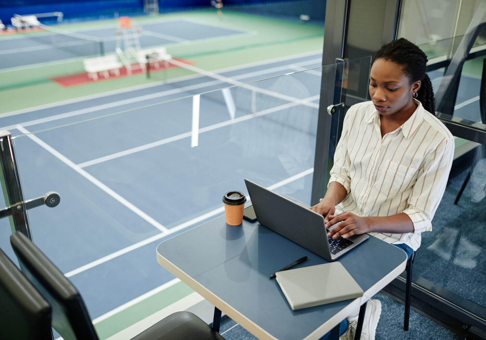 High angle portrait of young black businesswoman using laptop while working in sports training center